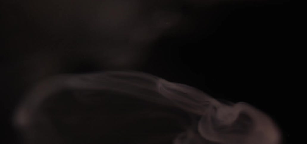 Blurry wisp of smoke rises against a muted, dark background