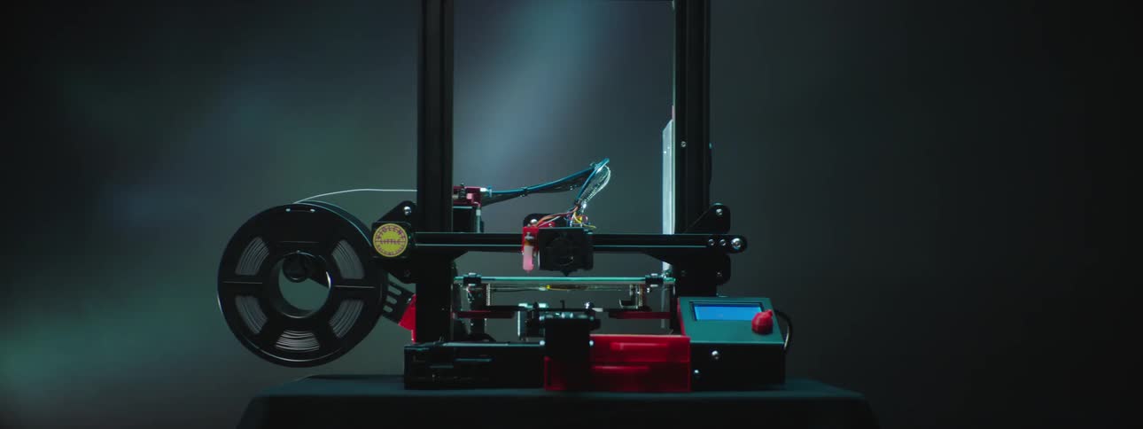 A 3d printer is slowly creating an item in a dark room