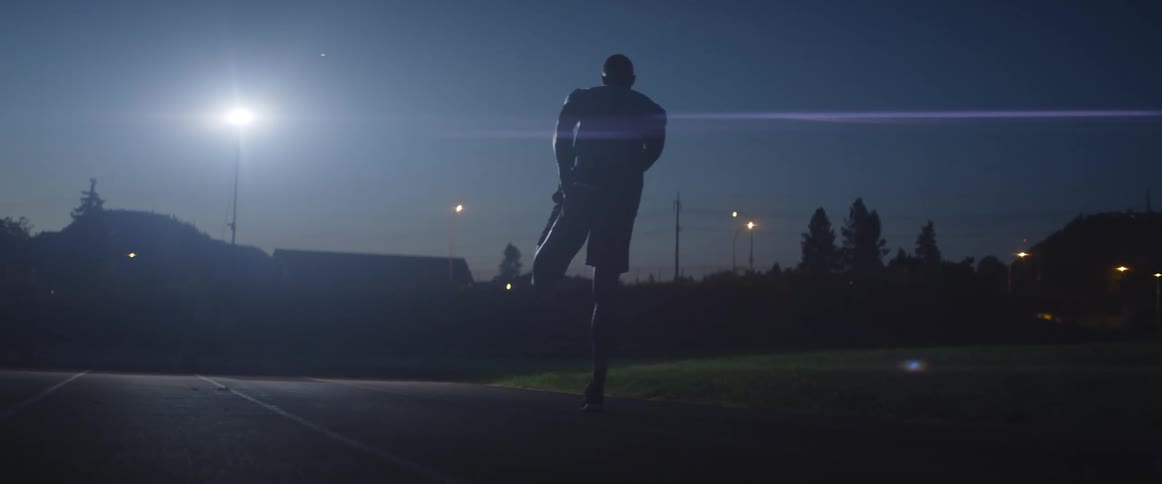 A man stretches on a dark race track