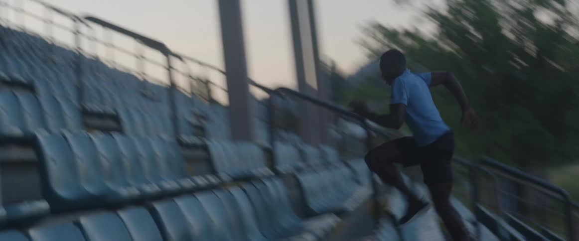 A man is running fast up the bleacher steps