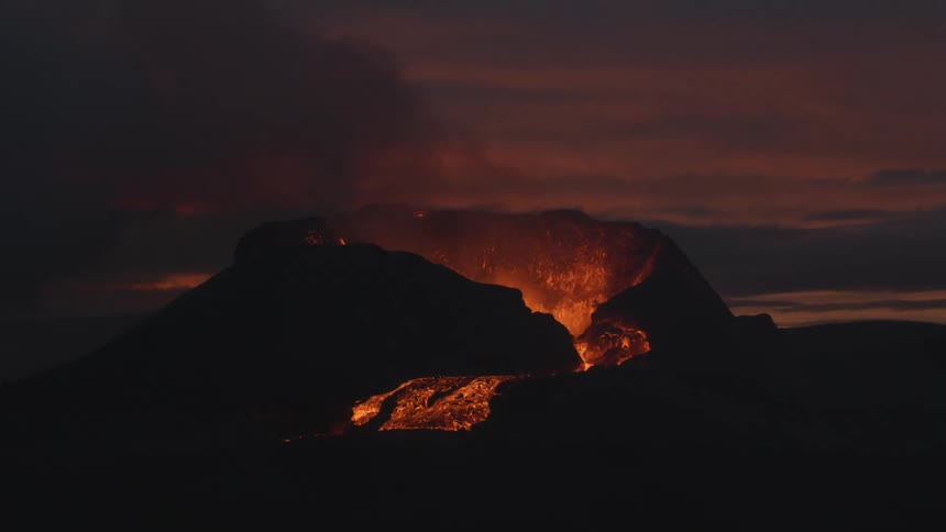 Lava bursting and flowing glowing orange at dusk