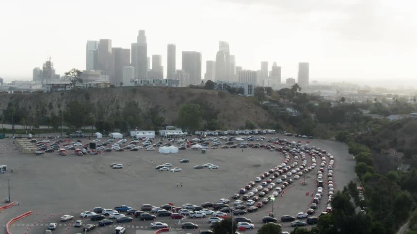 Rows of cars sit parked in the lot near the trees