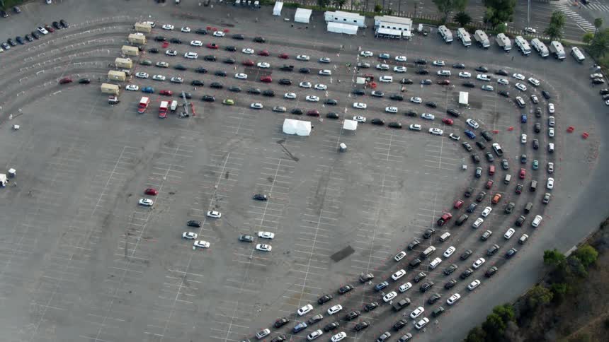 Vehicles lined up in a parking lot surrounded by trees