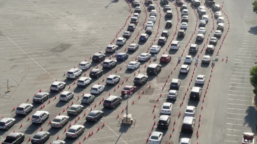 A parking lot with vehicles lined up between parking cones