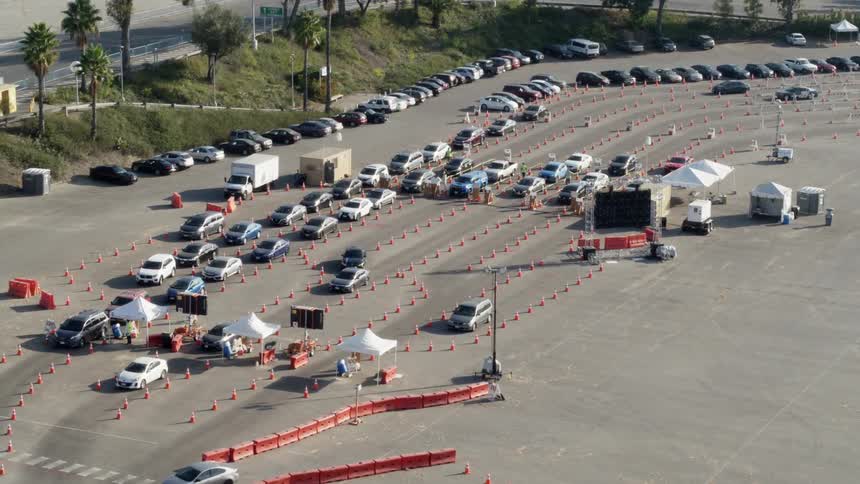 Traffic slowly travels in lanes designed by traffic cones in a parking lot during the day