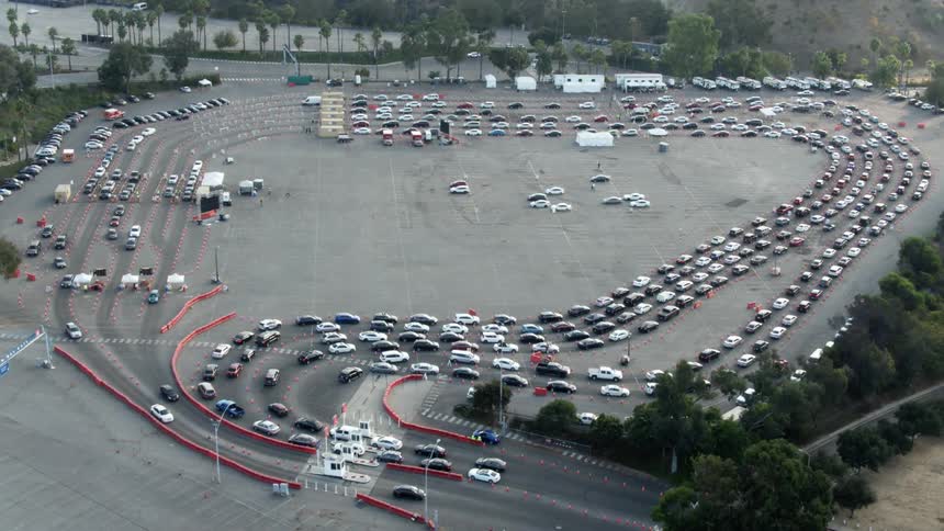 Cars wait in lines to enter temporary buildings before leaving lot