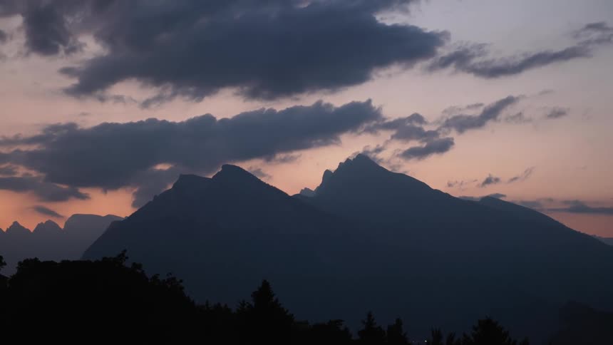 A view of some mountains in the distance with clouds above them