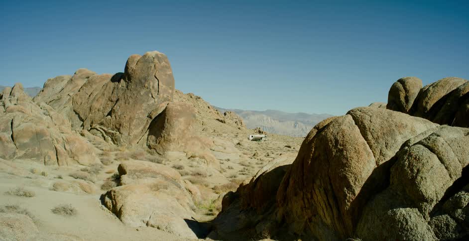 A recreational vehicle parked in a rocky section of desert under a clear blue sky