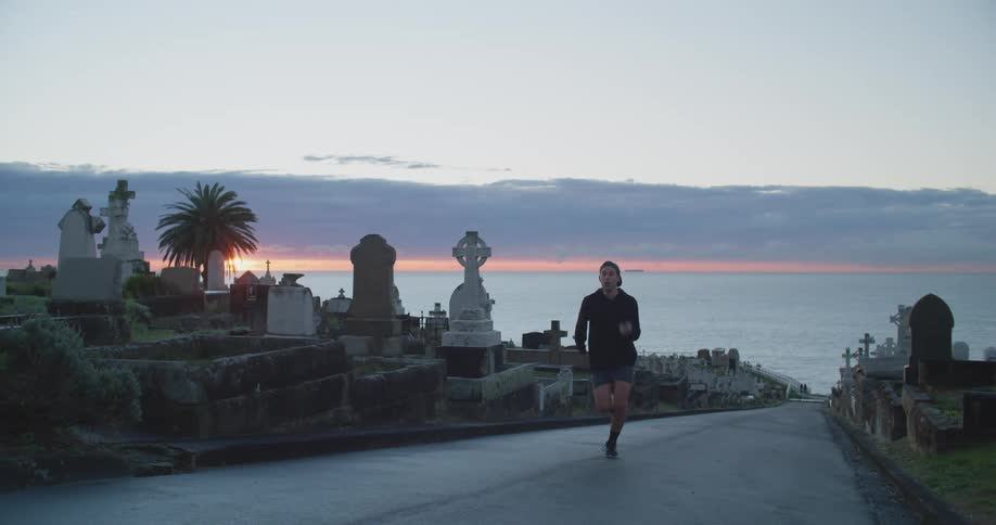 A man is jogging on a path outdoors at dusk