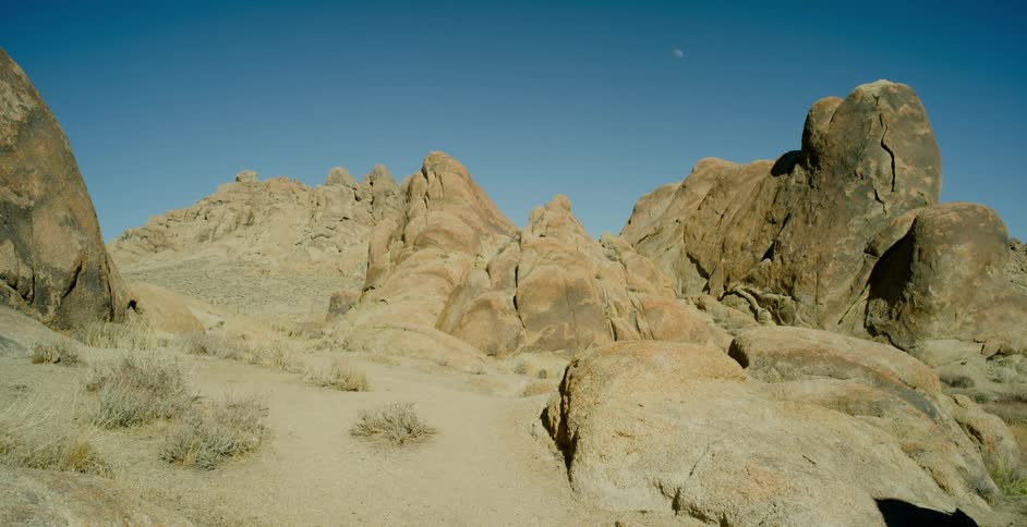 Jagged rock formations and desert brush under a bright blue sky