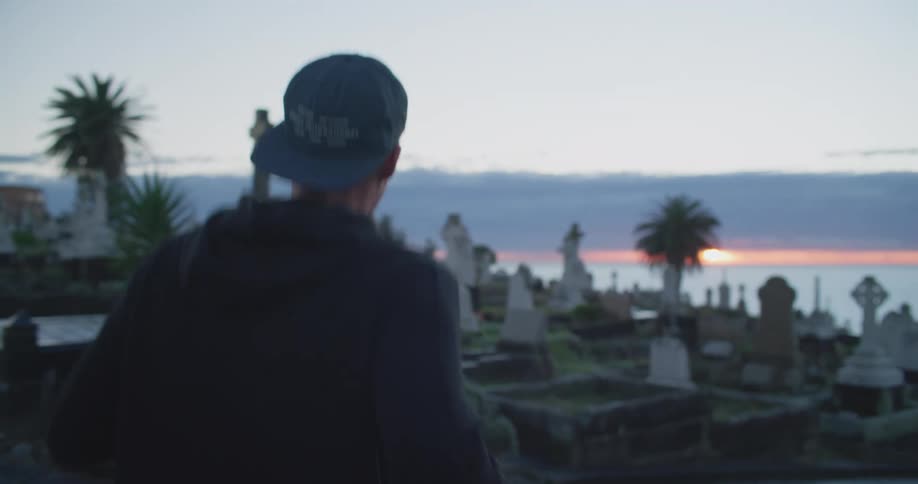 A man jogs through a cemetery on the coast at sunset