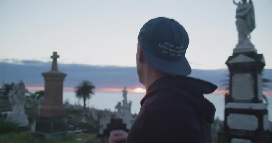 A man jogs through a cemetery that overlooks the ocean