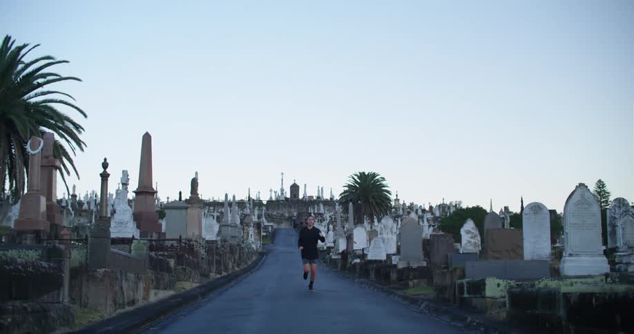 A man is jogging near a cemetery in spring