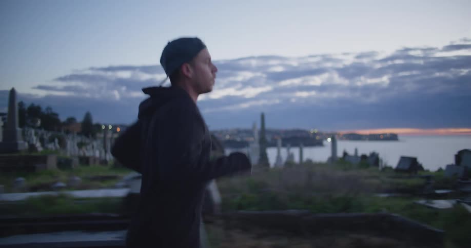 A young man jogs past a cemetery on the shore