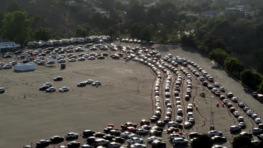 Traffic travels through a large parking lot in corridors created by traffic cones during the day