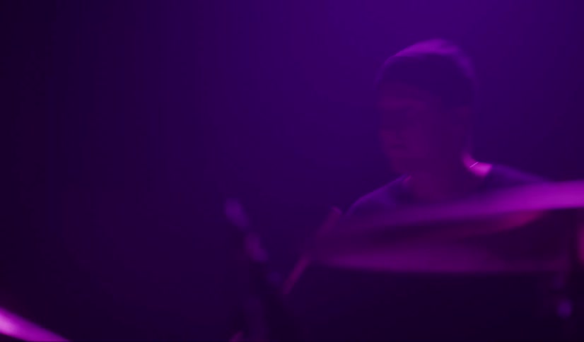 A man plays the drums in a hazy dark room