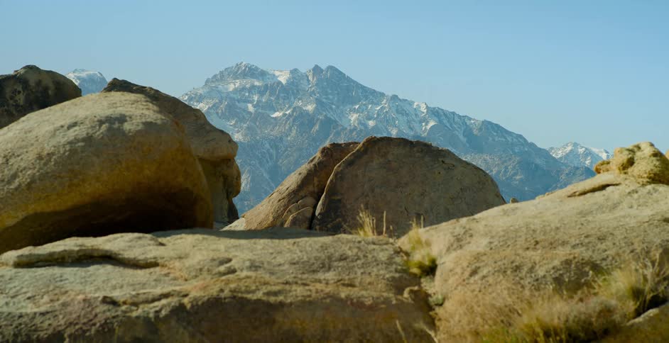 A huge mountain looms over several other large rocks and boulders