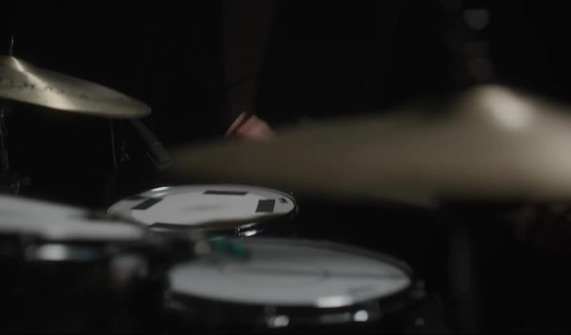 Man wearing a toque and earbuds plays the drums and cymbals with drumsticks