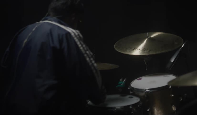 A person is sitting down and playing the drums