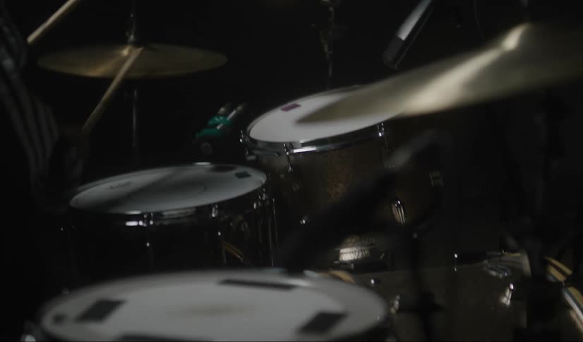 A man plays the drums in a dark room