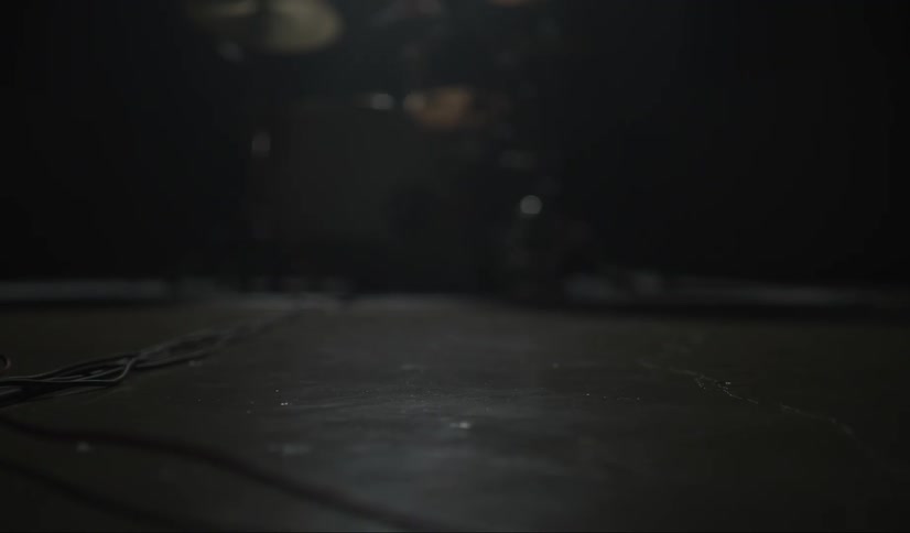 A man plays the drums on a dark stage