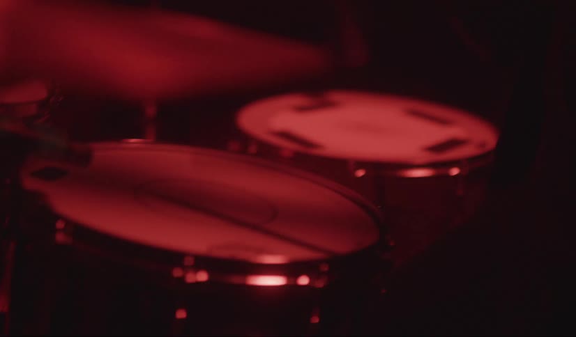 Man wearing glasses plays the drums and cymbals with drumsticks