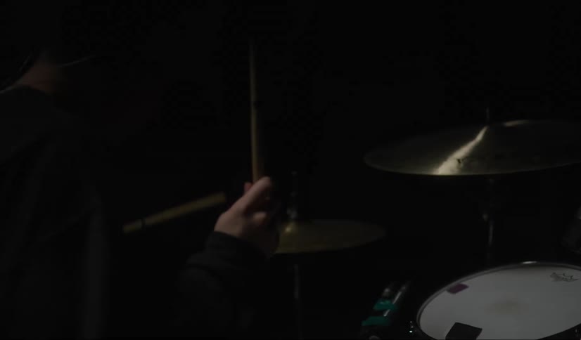 A musician plays the drums as lights flicker and strobe