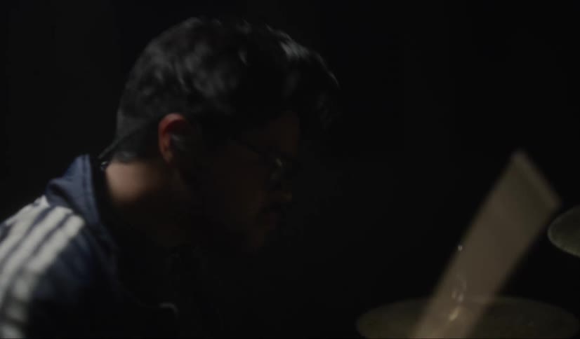 A man is playing the drums in the dark