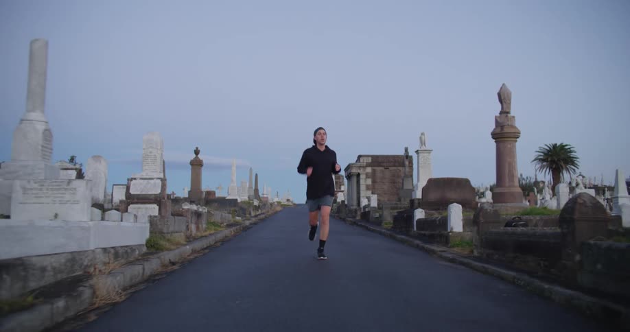 A man jogs past tombstones in a crowded cemetery