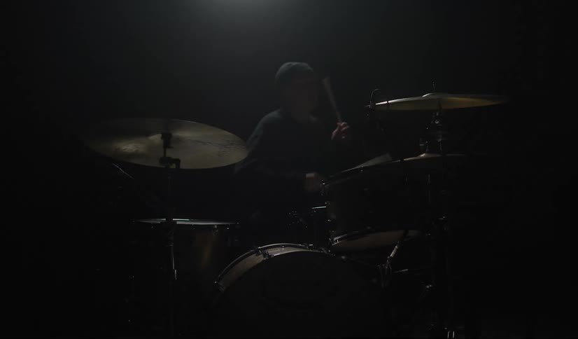 A man playing drums on a stage with strobe lights