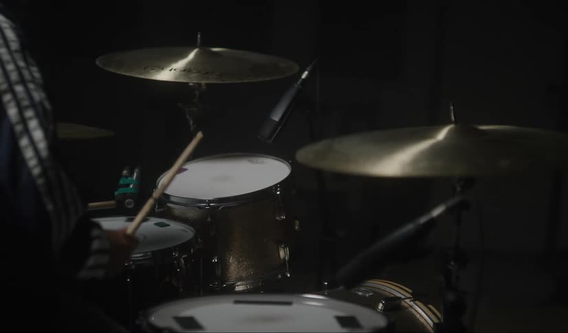 A person is playing the drums in the dark