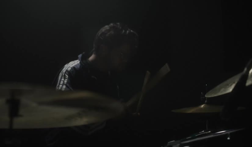 Man plays the drums as lights flash around him