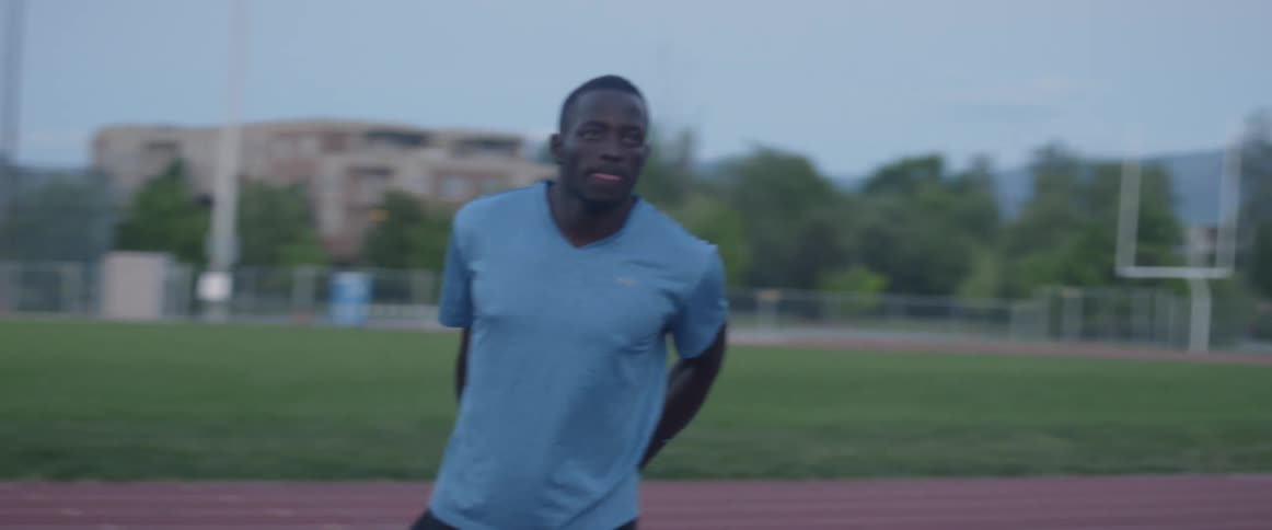 Mans stretches legs on a track at night