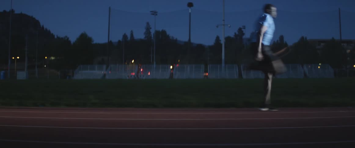 A man runs on a track at night