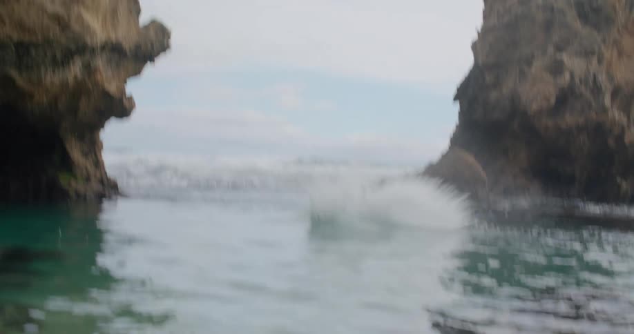 A man in swim trunks jumps off a cliff into the ocean