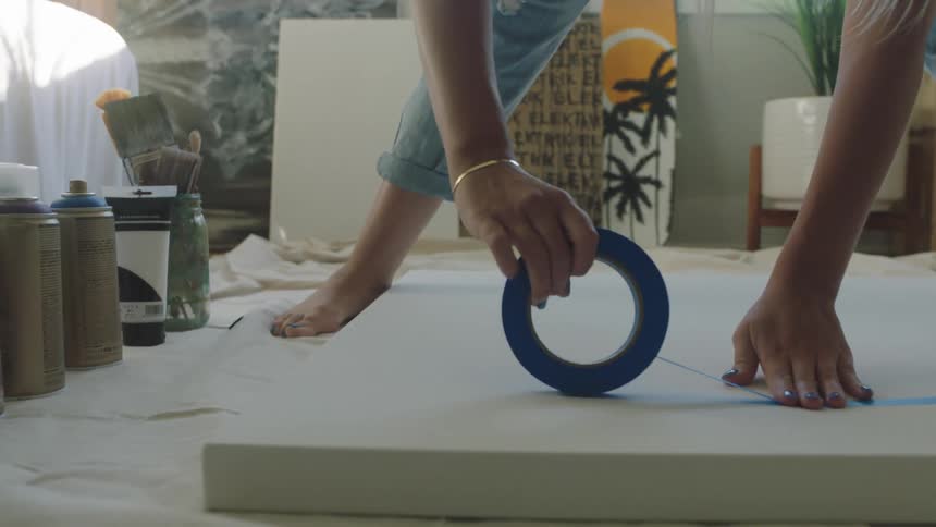 A woman putting tape on a canvas