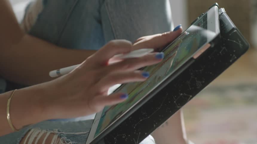 A woman is using a stylus on a tablet
