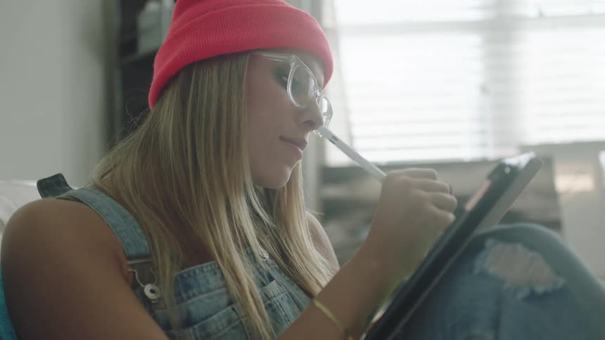 A woman uses a stylus to write on her tablet