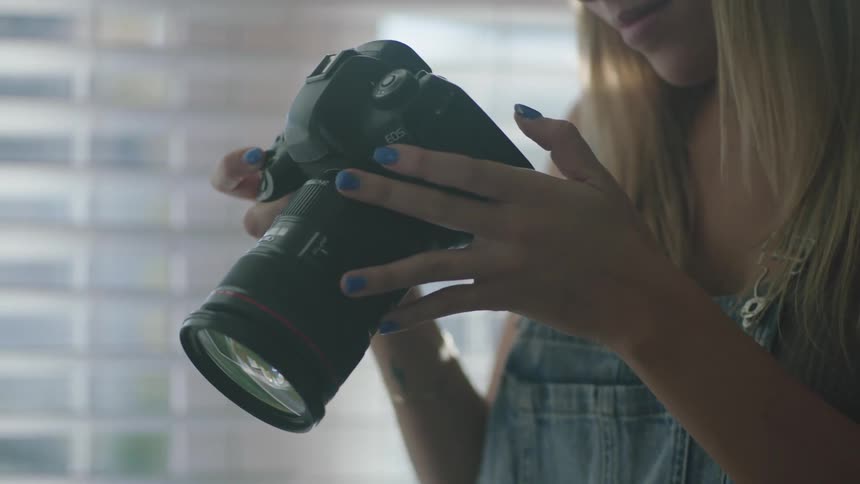 A woman takes a photo with her digital camera and holds it down to look at the screen