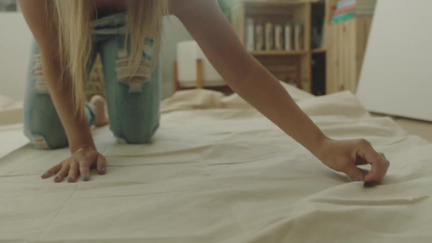 A woman is spreading a tarp in her living room