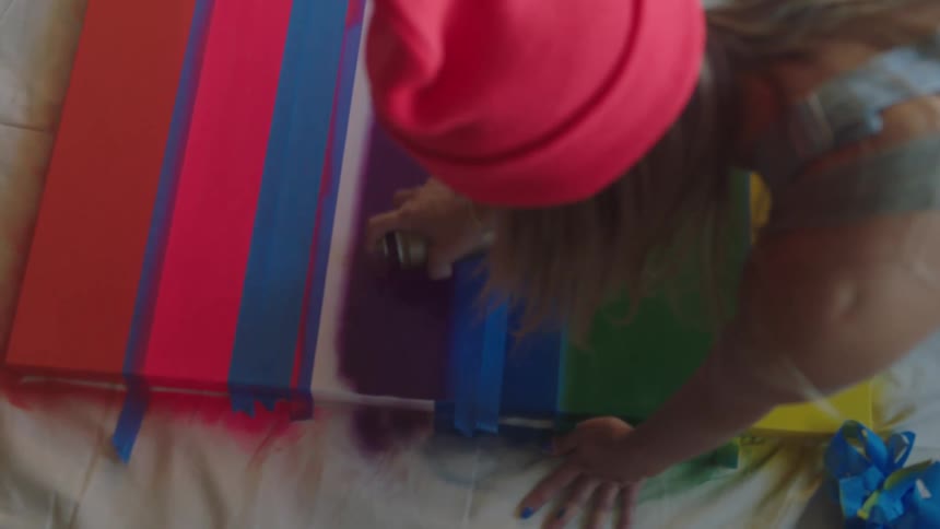A woman spray paints lines on a large board