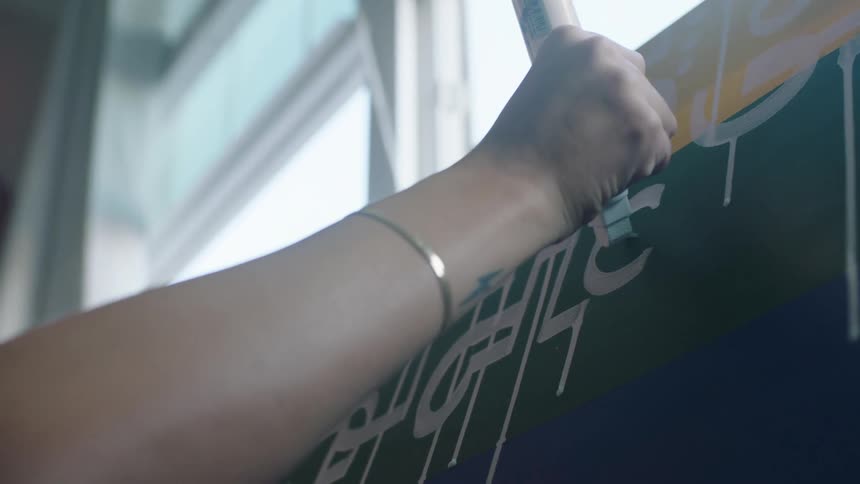 A woman adds white paint shapes to a canvas