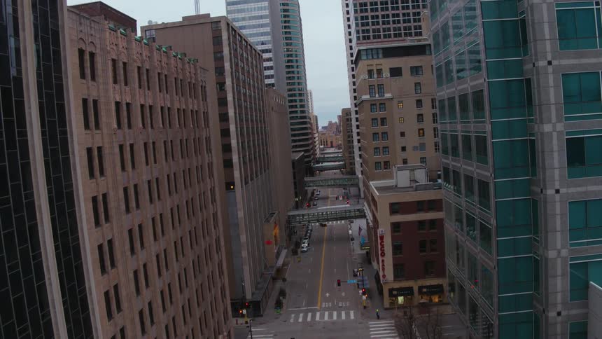 Cars travel on a city street between buildings downtown