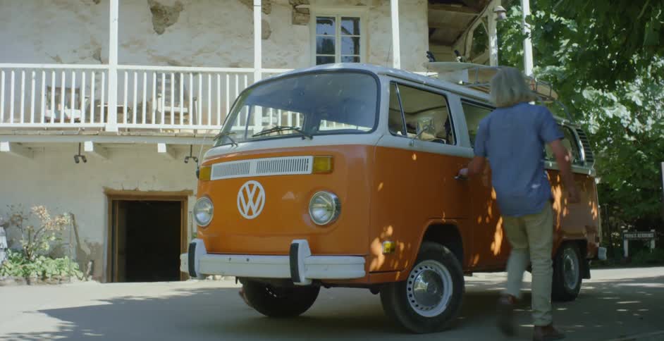 A man and woman enter an orange van
