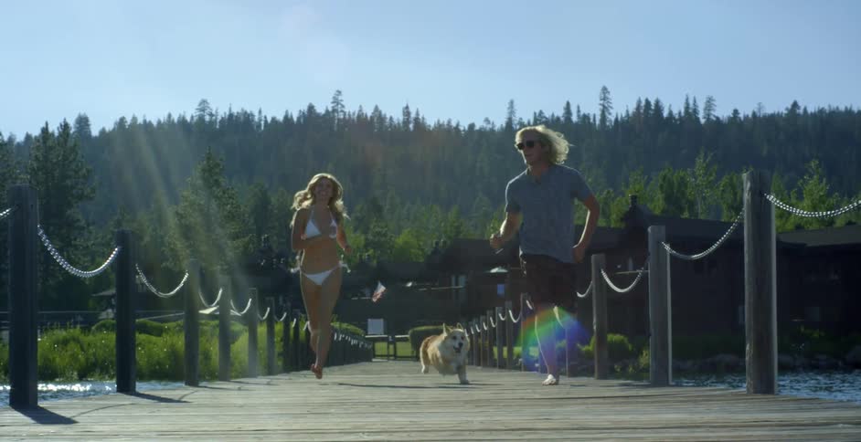 Man and woman run with their dog on a dock