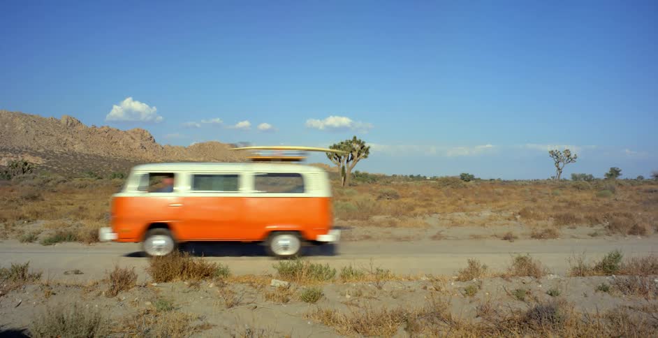 A volkswagen bus travels on a desert road