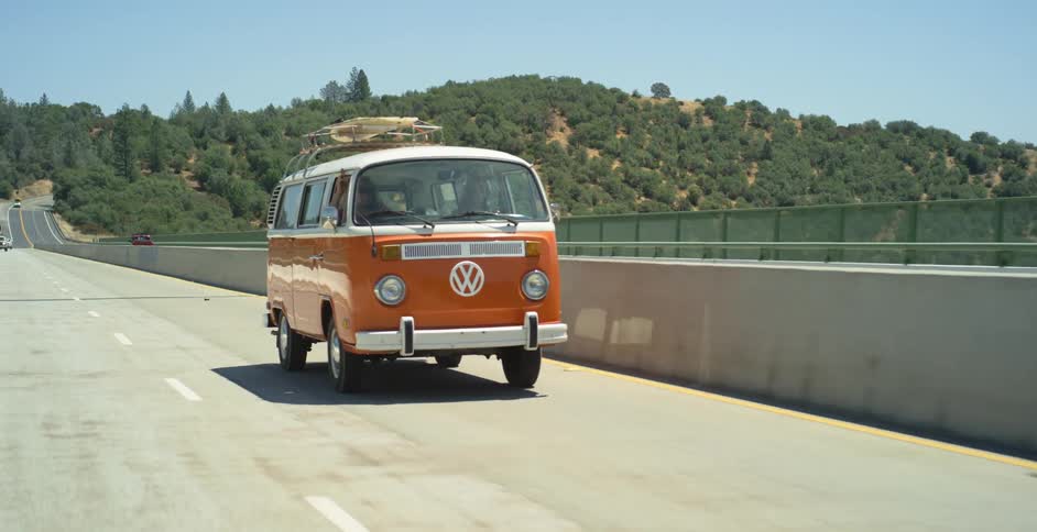 Orange van drives down a highway on a sunny day