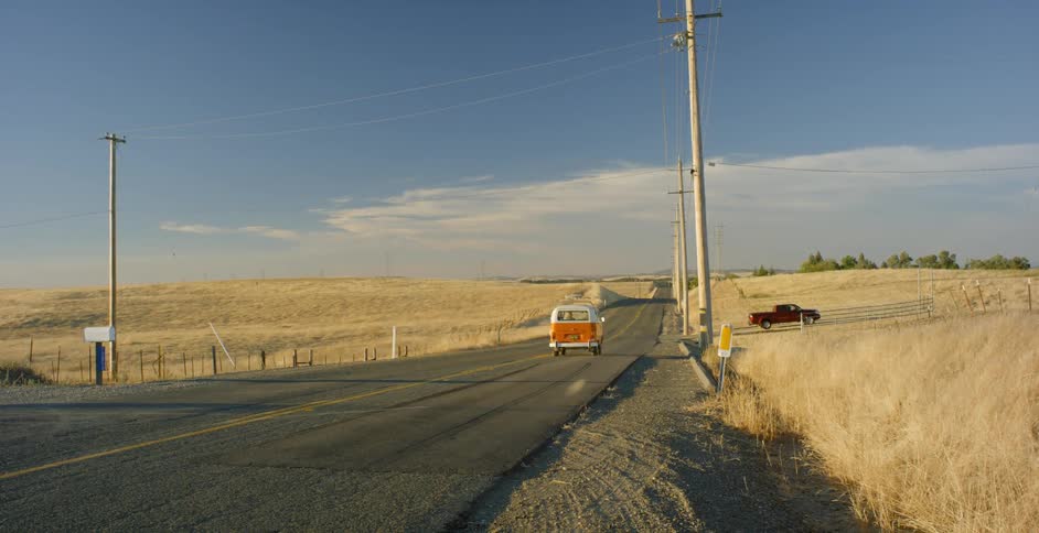 An orange volkswagen van turns onto the road