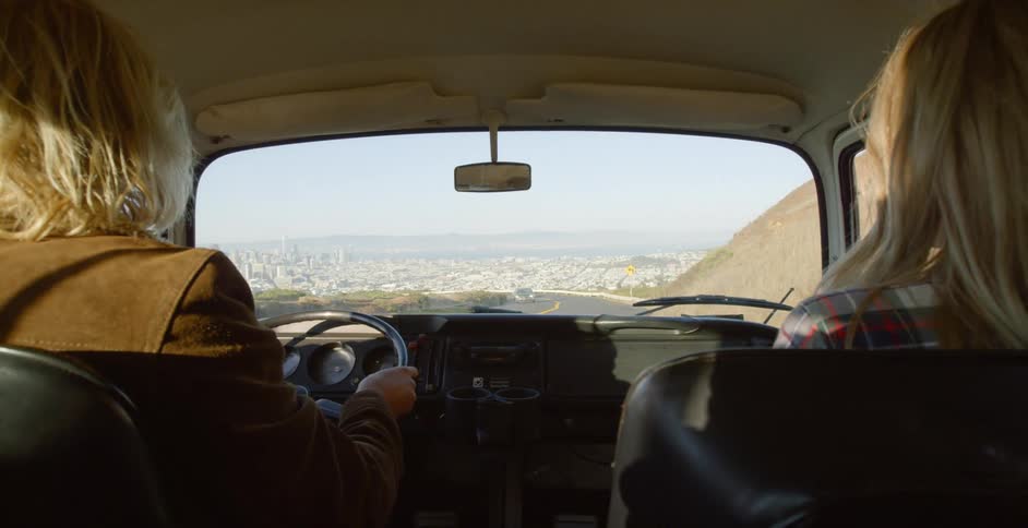 Two people are driving down the road towards a large city