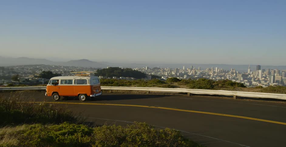 Orange and white van travels around a bend on a highway